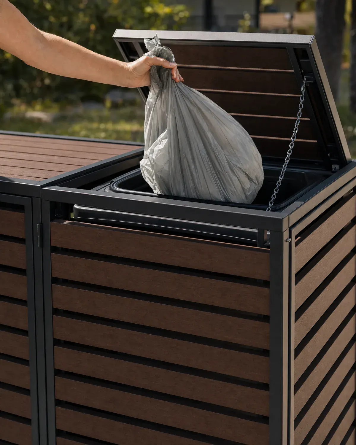 Hand tilt het deksel van de HAVN Linea op en gooit een vuilniszak in de kliko